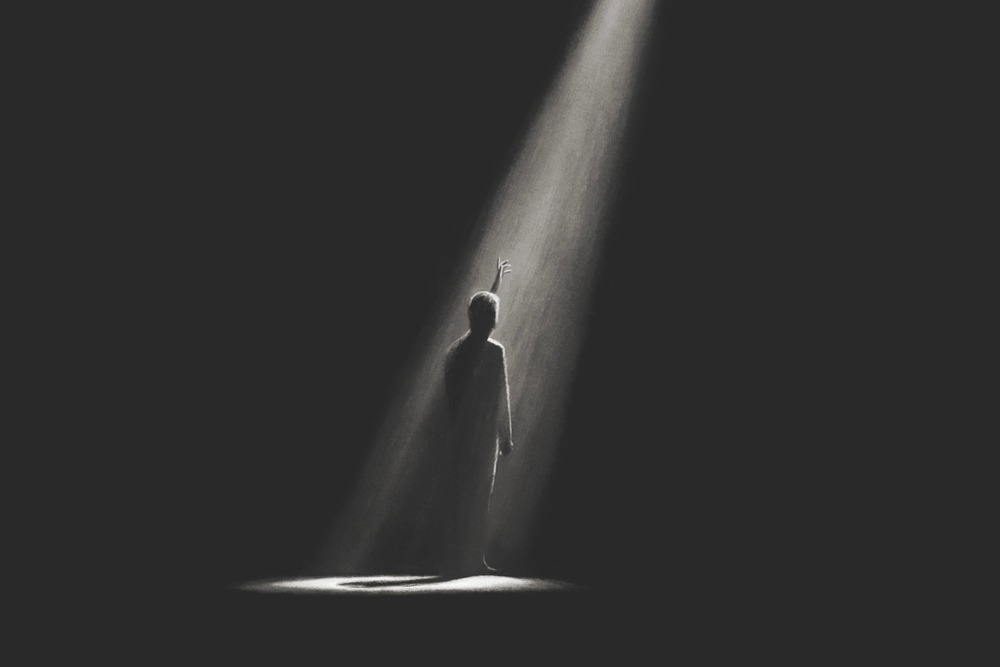 Silhouette standing in darkness reaching toward light, symbolizing faith tested in the shadows