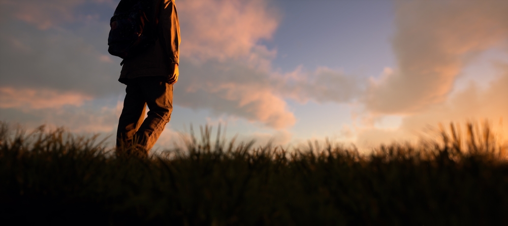 Africa personal transformation concept with a person walking through grass at sunset, symbolizing growth, resilience, and a journey from shadows to light