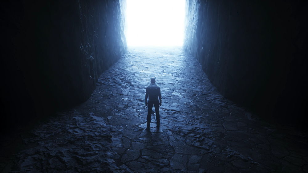 Suffering and redemption concept with a lone figure standing in darkness facing a bright light, symbolizing hope, transformation, and spiritual growth